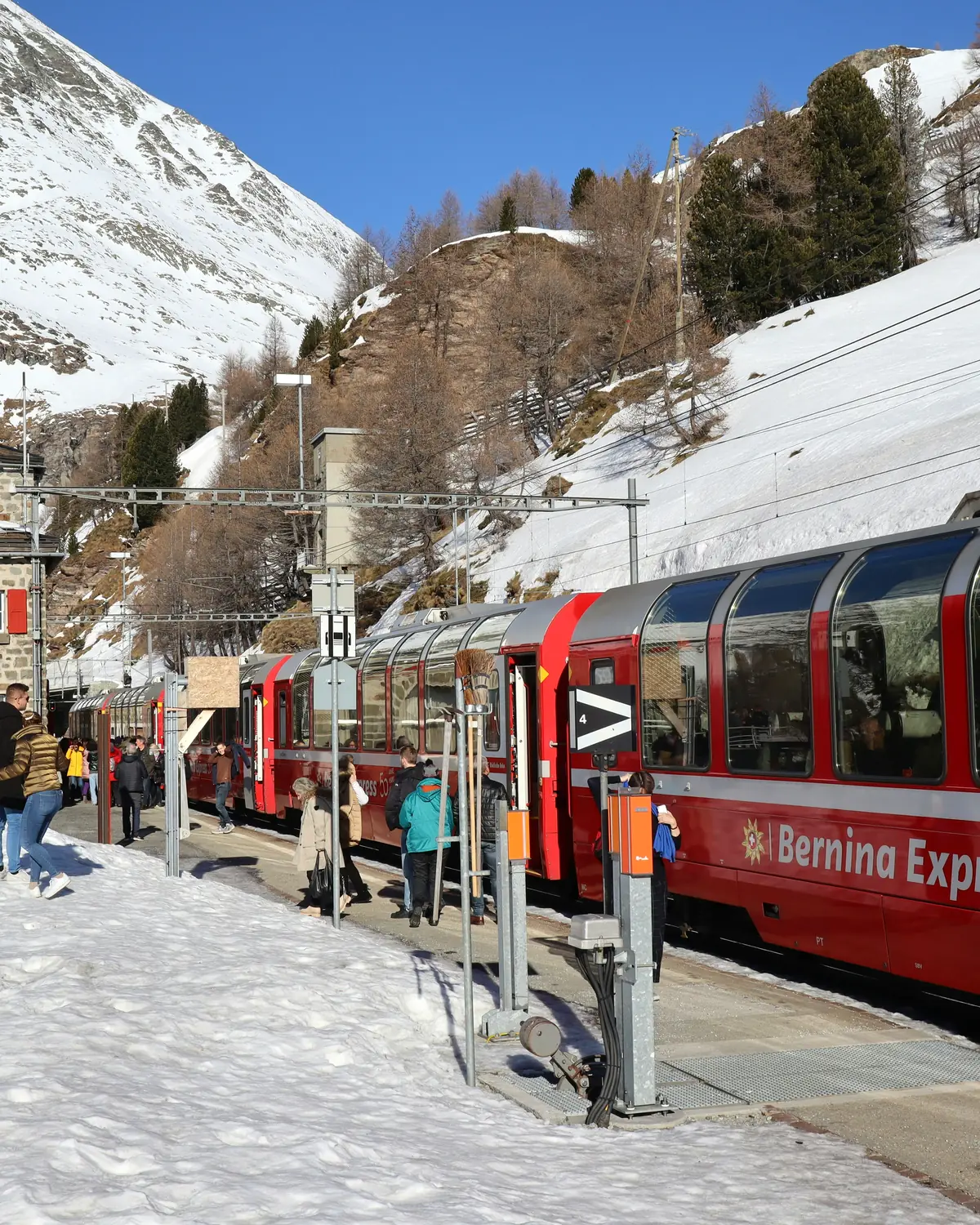 A red Bernina Railway train descending toward Tirano on the UNESCO Bernina line — the route covered by the 2026 timetable on this page