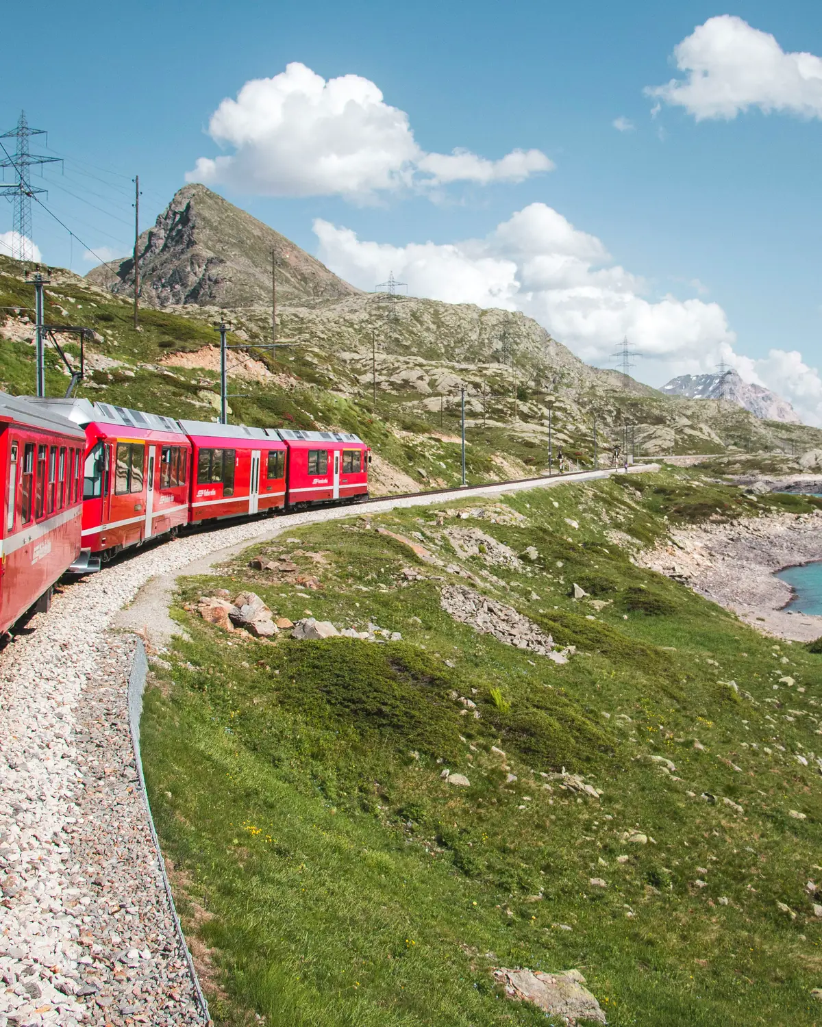 Red Bernina Railway train near Lago Bianco at the Bernina Pass on a sunny summer day — UNESCO World Heritage line, Switzerland